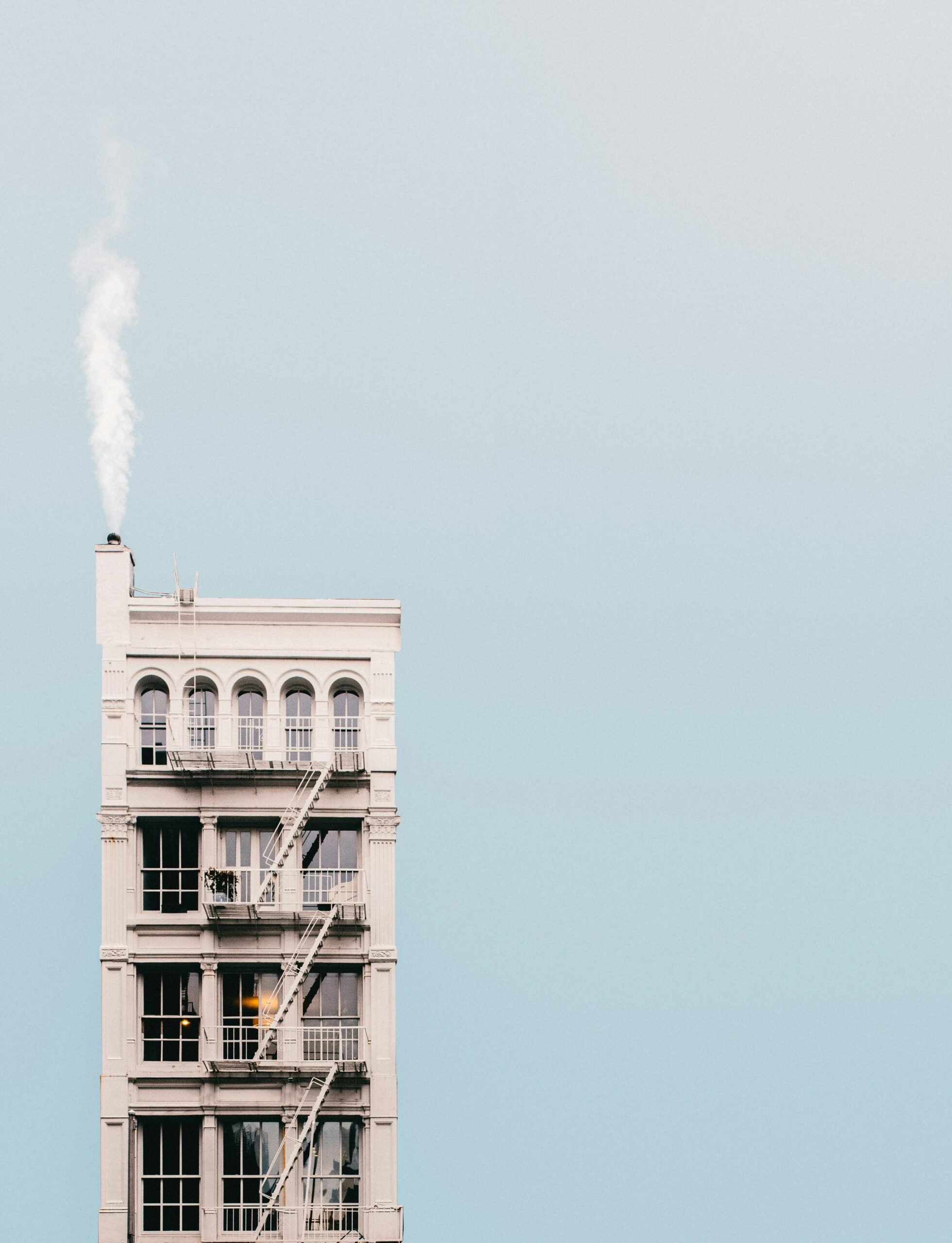 A minimalist photo of a high-rise building with smoke emerging from the chimney in New York City.