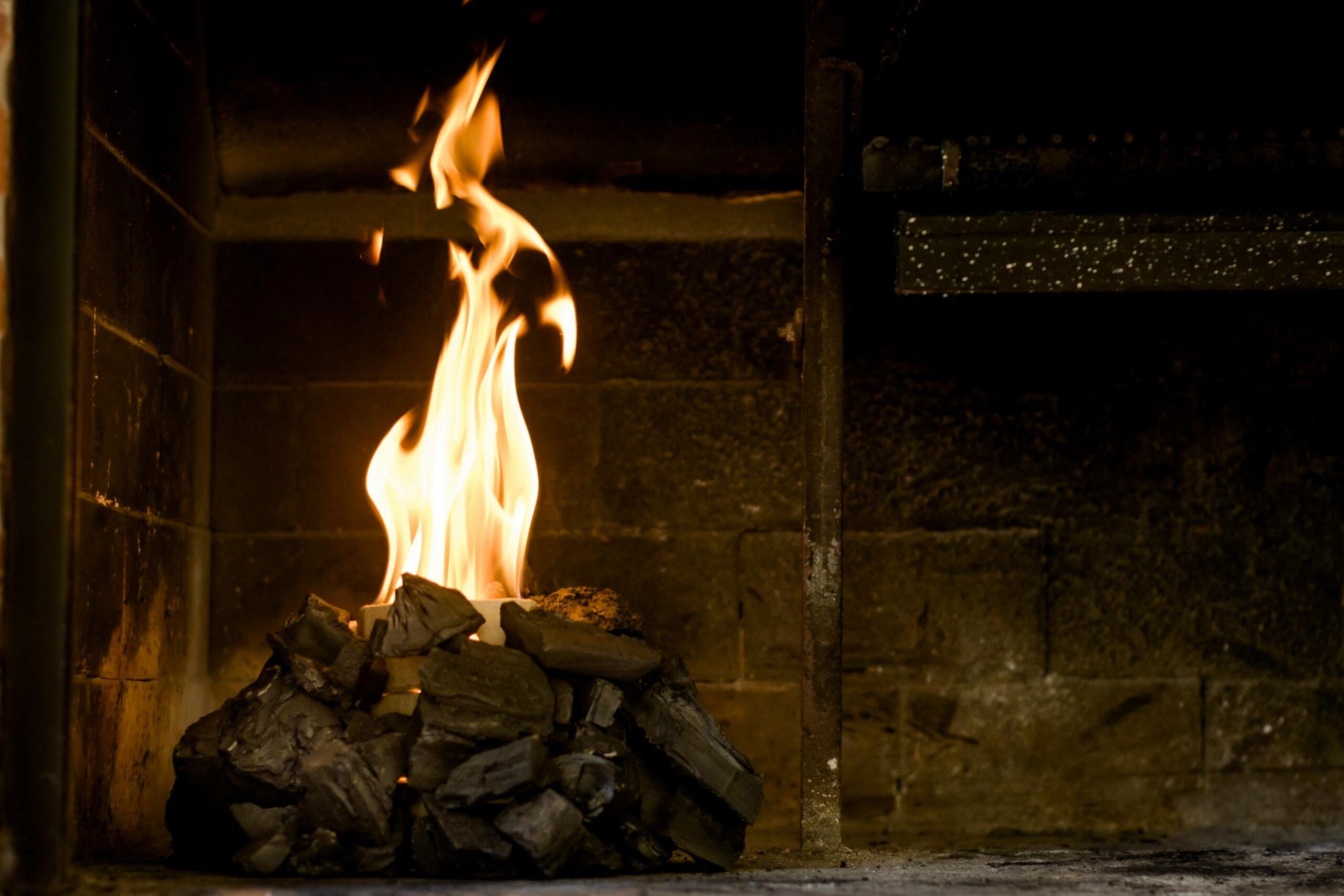 Relaxing indoor setting with burning coals and flames producing warmth and light.