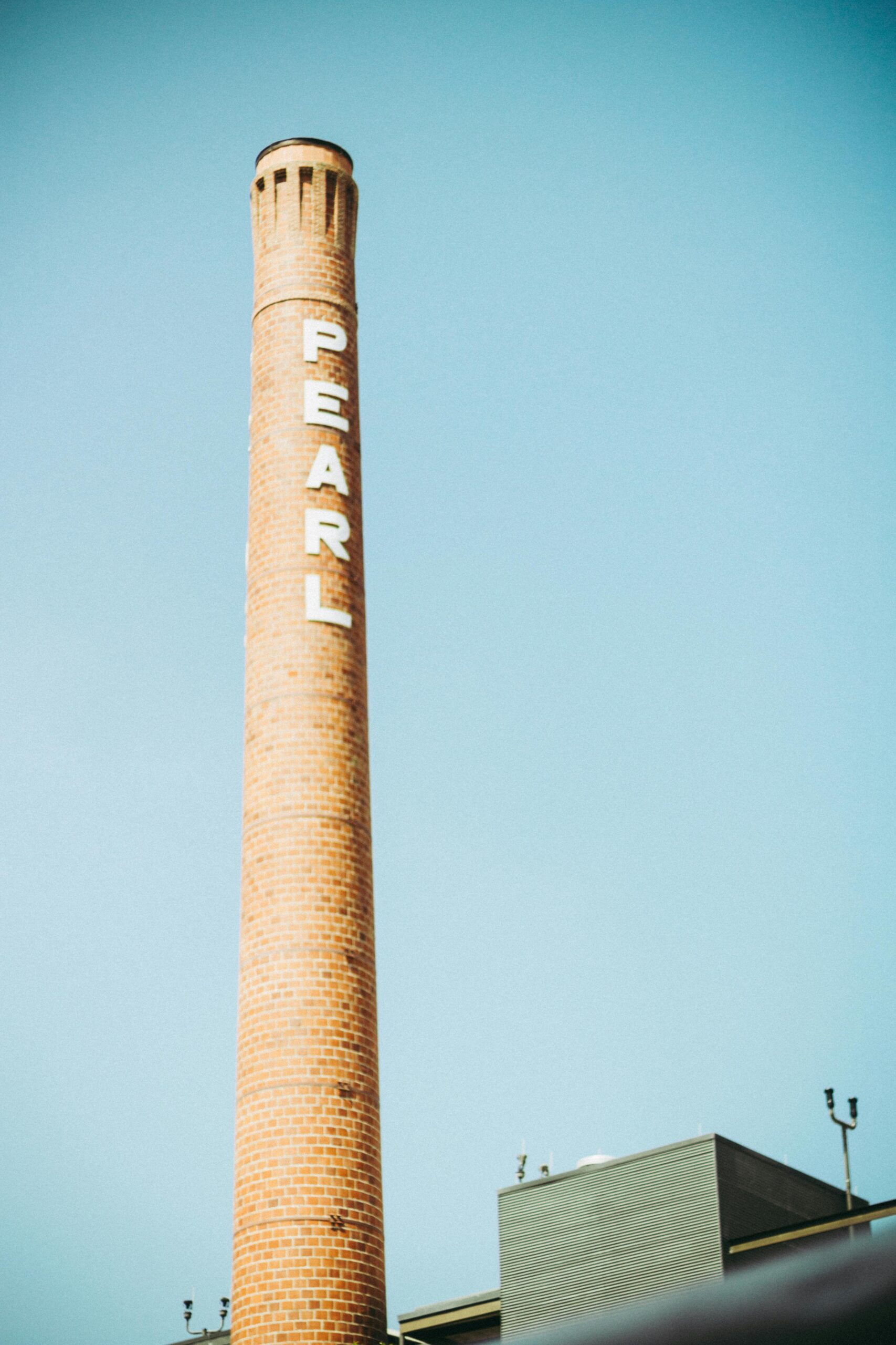 A towering industrial chimney labeled 'PEARL' against a clear sky in San Antonio.